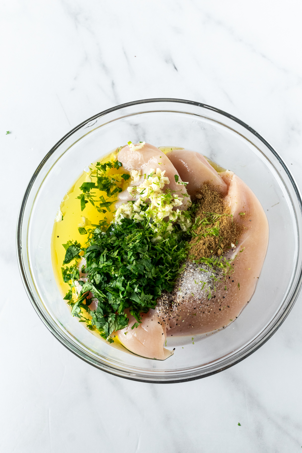 chicken marinade with lime and cilantro in a bowl on a white table.