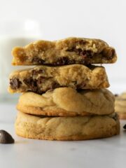 stacked soft chocolate chip cookies on a white table.