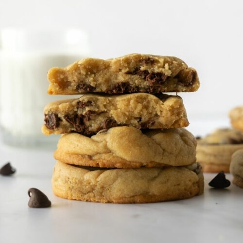 stacked soft chocolate chip cookies on a white table.