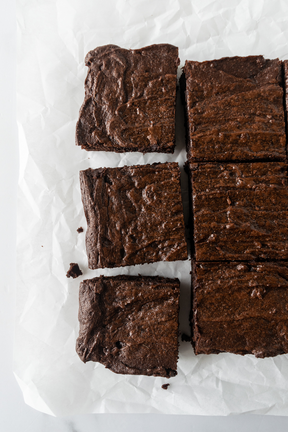 brownies on white parchment paper cut into squares.