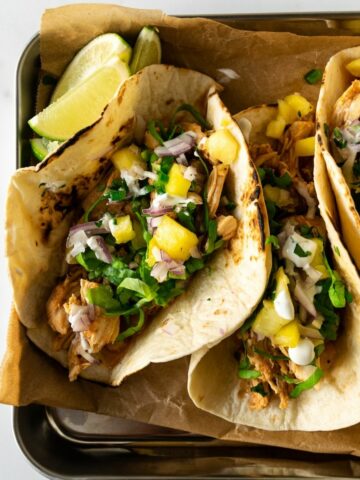 Switch up your weeknight dinners with these delicious Hawaiian chicken tacos topped with a fresh jalapeño pineapple salsa. This easy, slow cooker recipe requires minimal effort– just set and forget it.