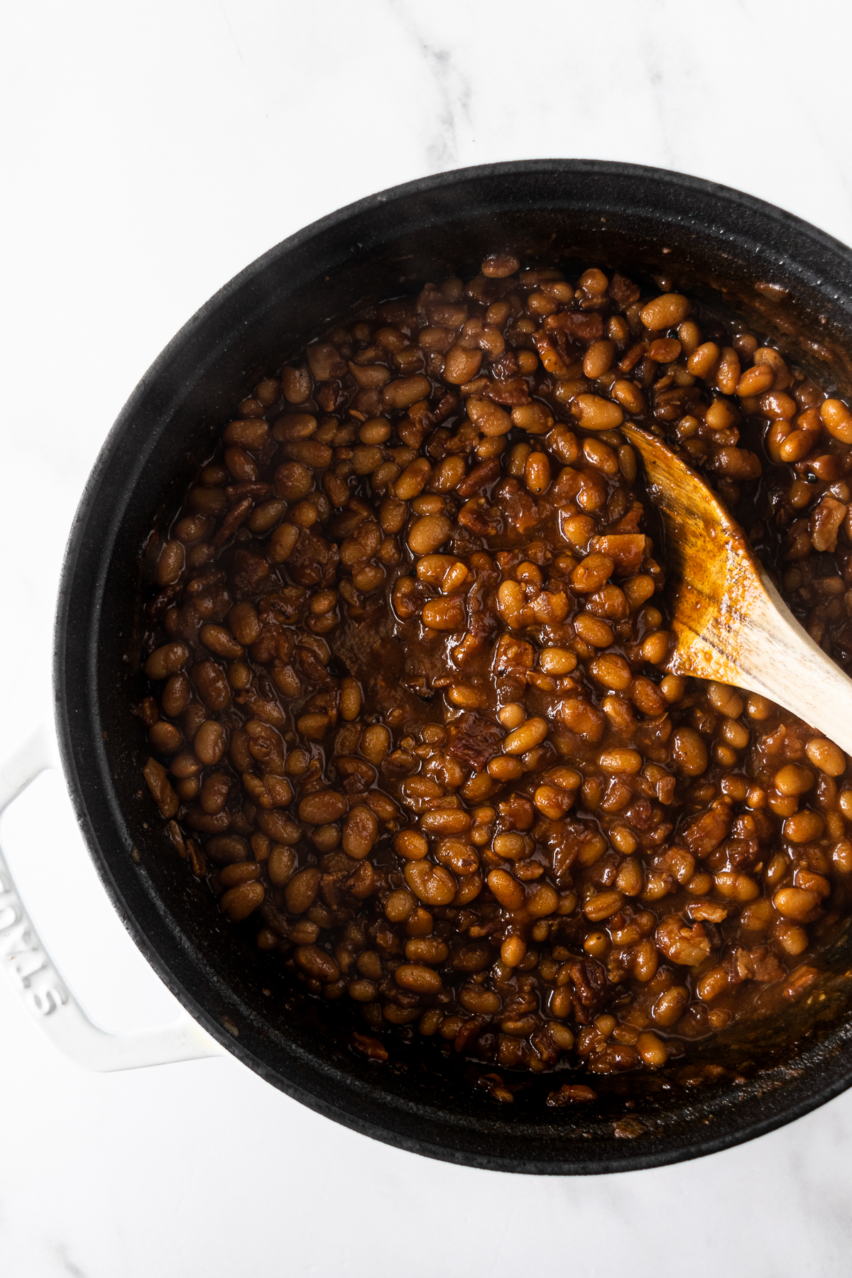 baked beans in a black pot with a wooden spoon.