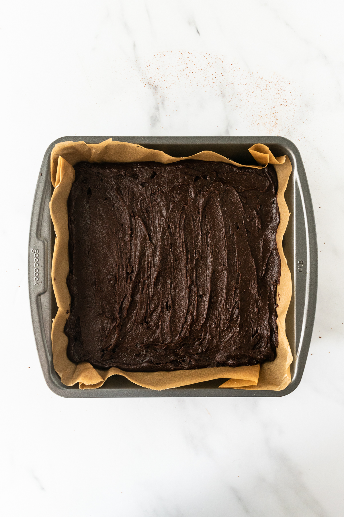 brownie batter in a square baking pan lined with parchment paper.