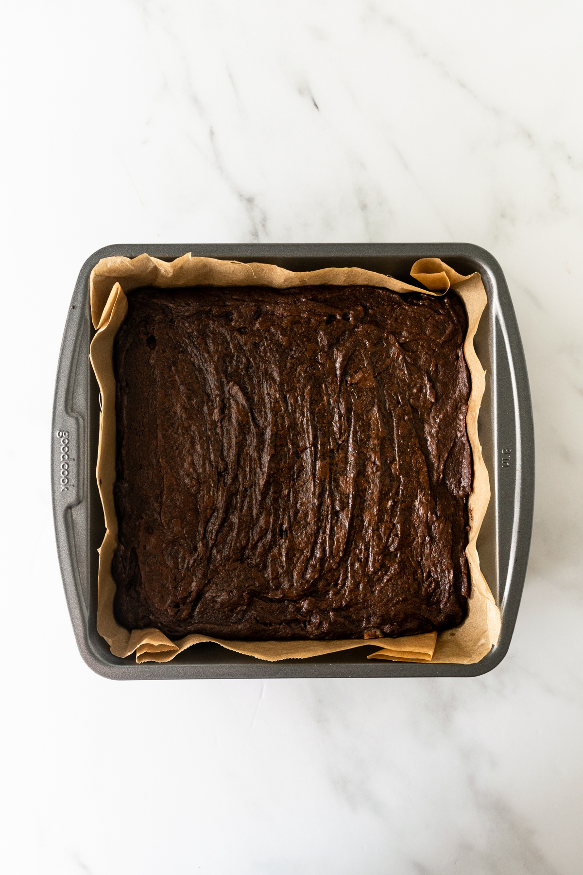 baked brownies in a square baking pan lined with parchment paper.