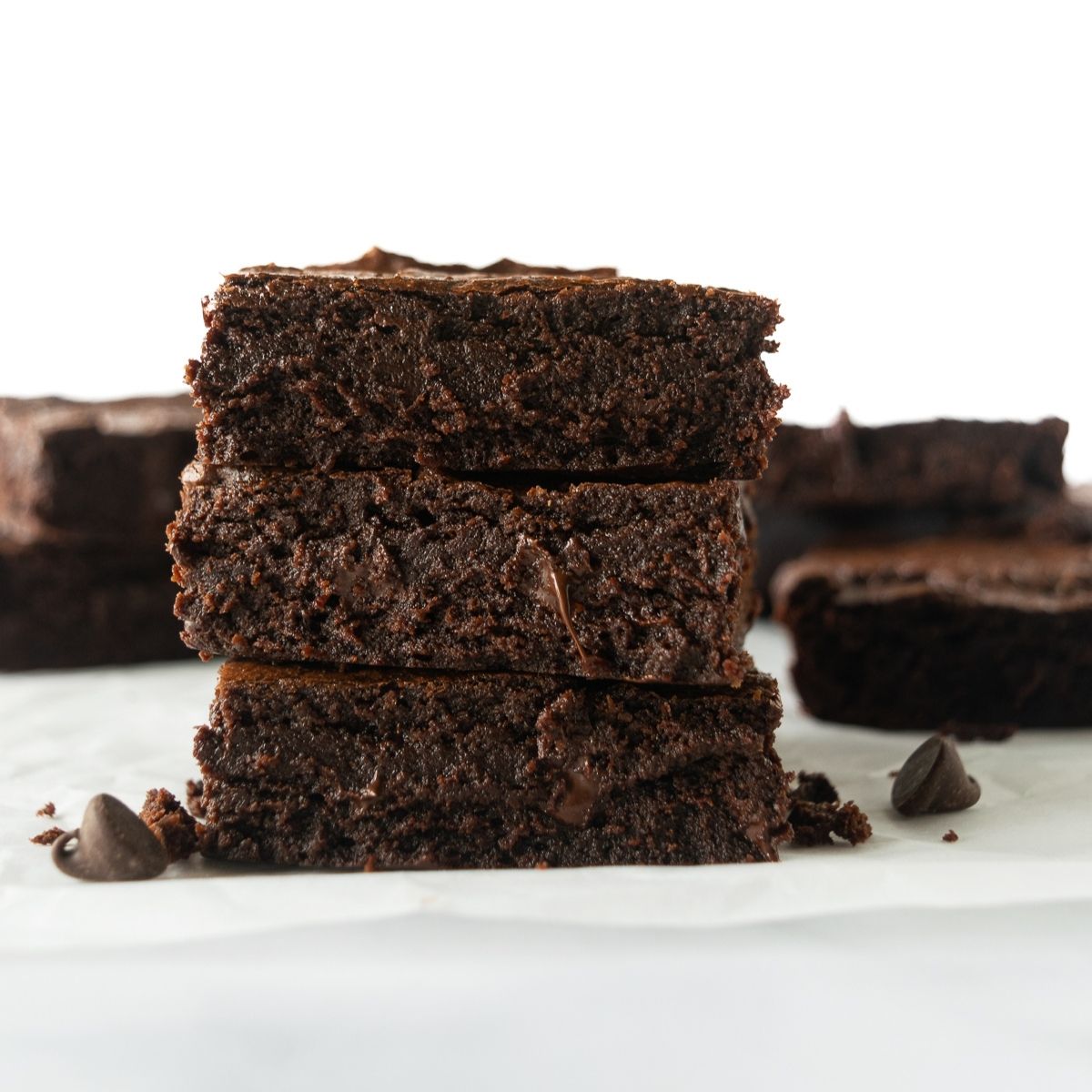 three stacked brownies on a white table.