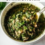 Argentinian chimichurri sauce in a white bowl with a spoon.