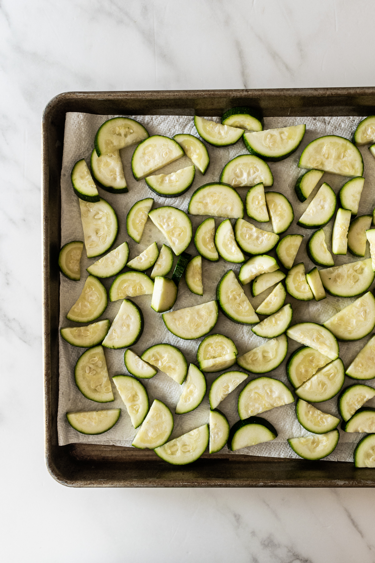 zucchini slices on a paper towel-lined baking sheet.