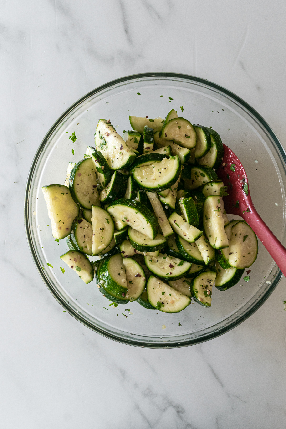 zucchini slices with seasonings in a bowl on a white table.