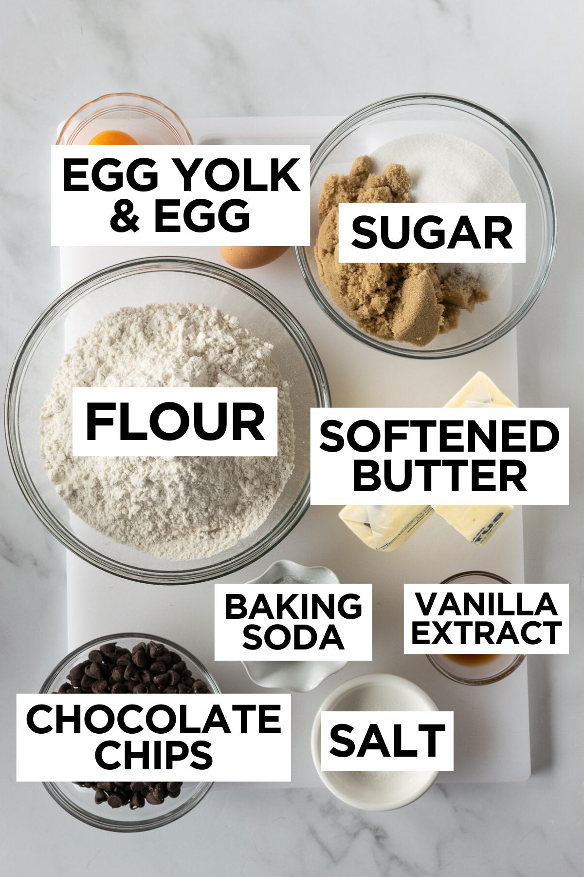 ingredients for soft chocolate chip cookies in bowls on a white table.