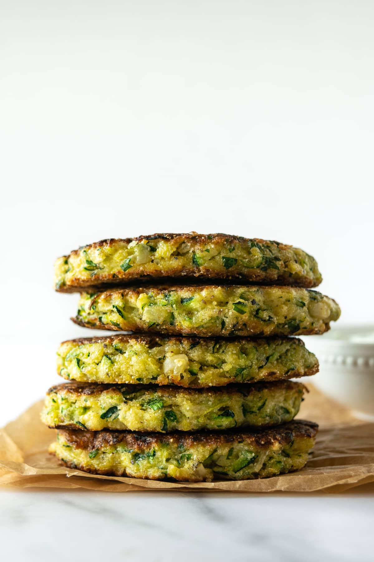 stack of zucchini fritters on parchment paper.