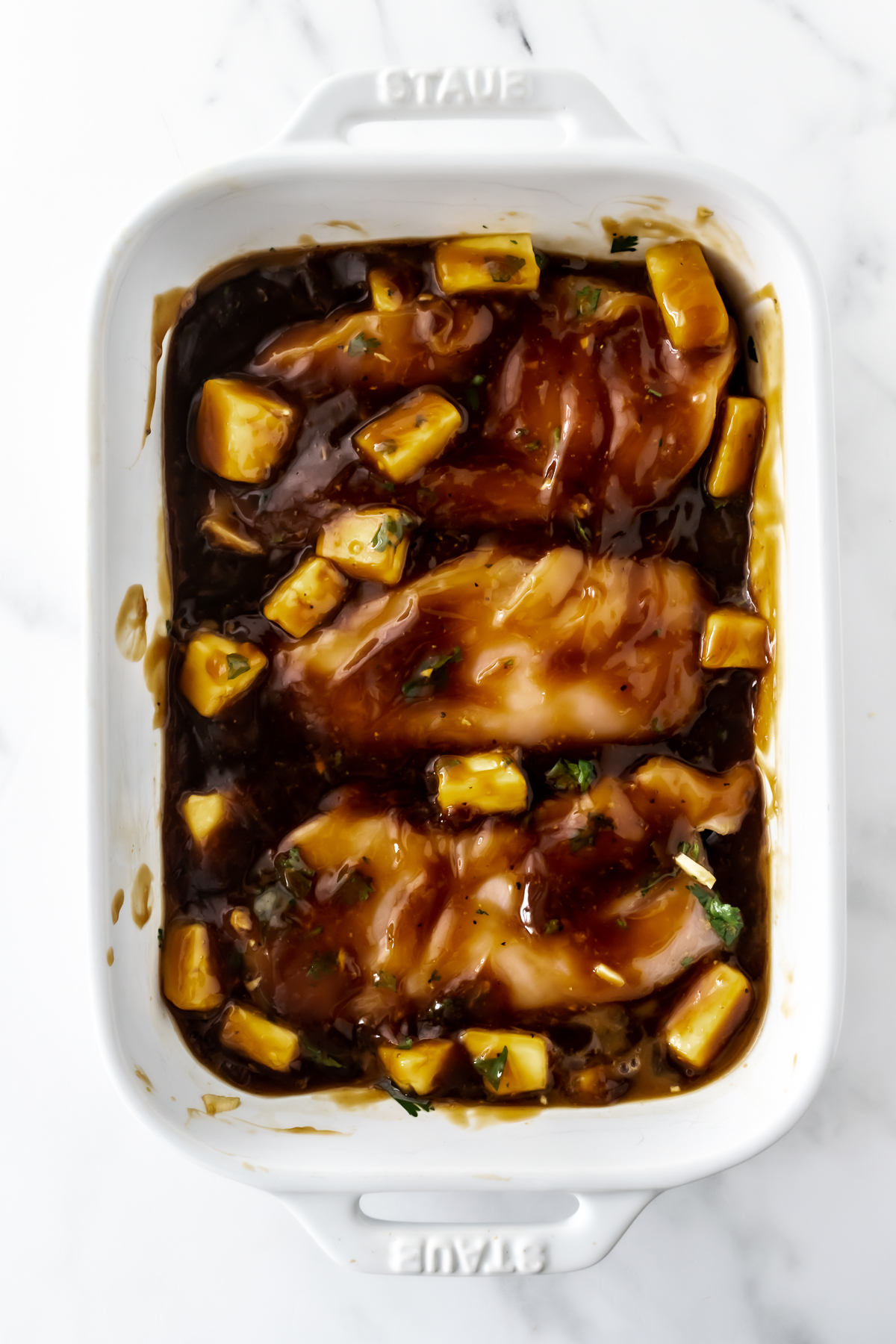 baked chicken teriyaki with pineapple in a white baking dish.