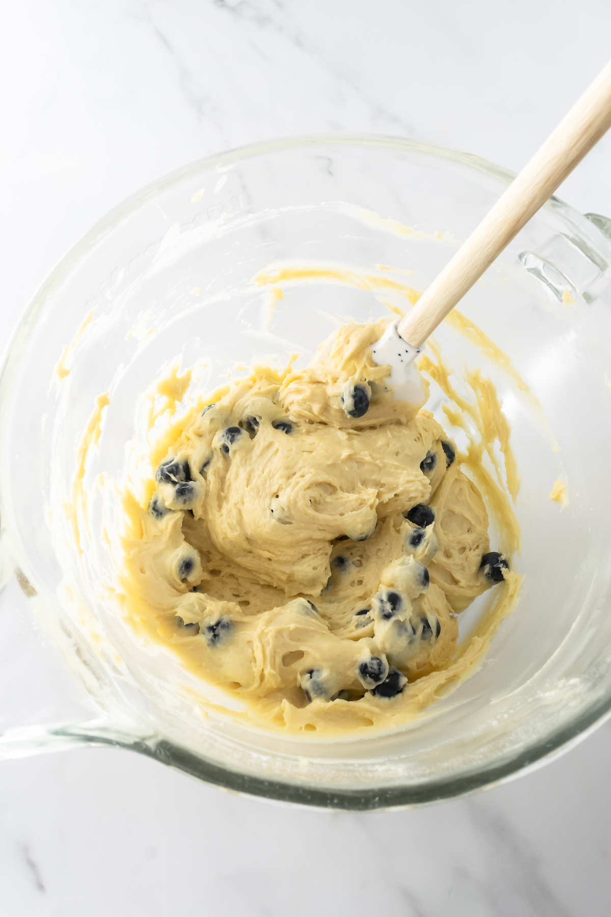 blueberry coffee cake batter mixed with blueberries in a mixing bowl.