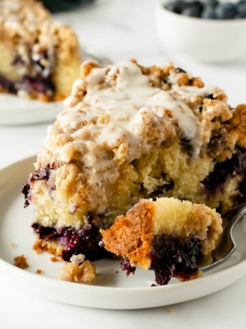 This blueberry crumb cake features a moist, tender, buttery vanilla breakfast cake studded with juicy blueberries, and topped with a thick layer of cinnamon brown sugar crumble topping. Finish it off with a drizzle of vanilla icing or a dusting of powdered sugar to make an impressive breakfast coffee cake that everyone will love!