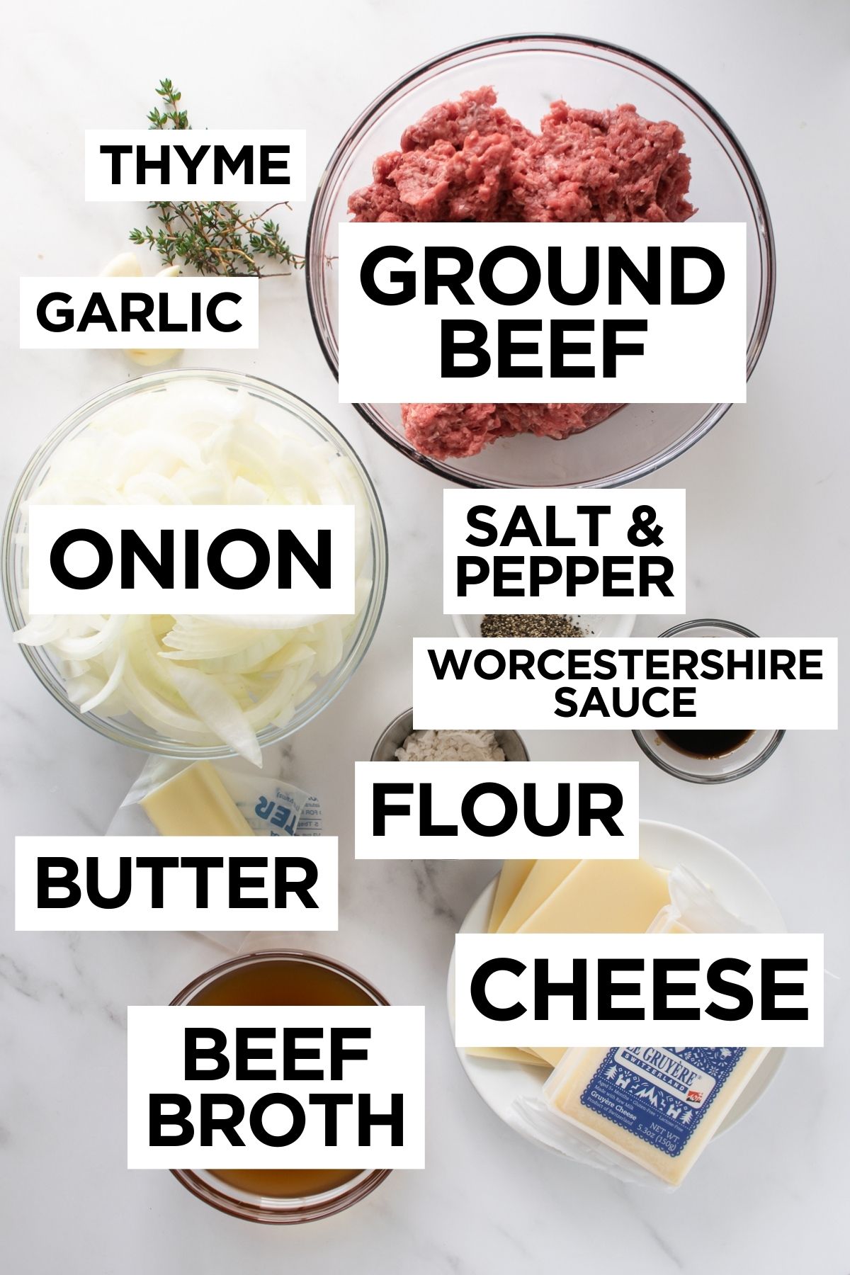 ingredients for French onion burgers in bowls on a white table.