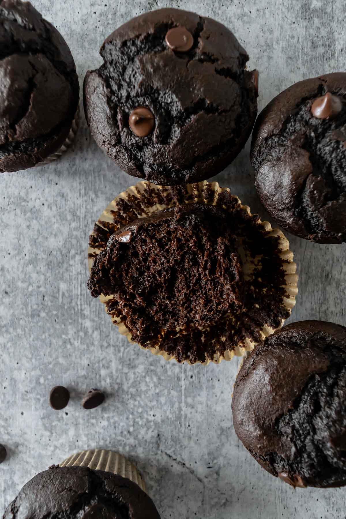 overhead shot of chocolate pumpkin muffin cut in half sitting in a liner.