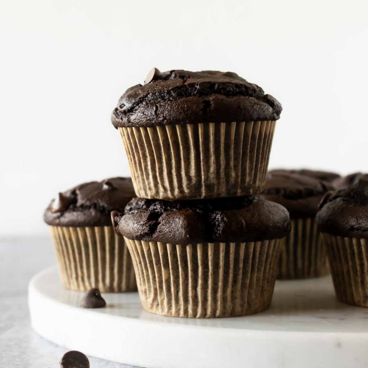 stacked pumpkin chocolate muffins on a marble board.