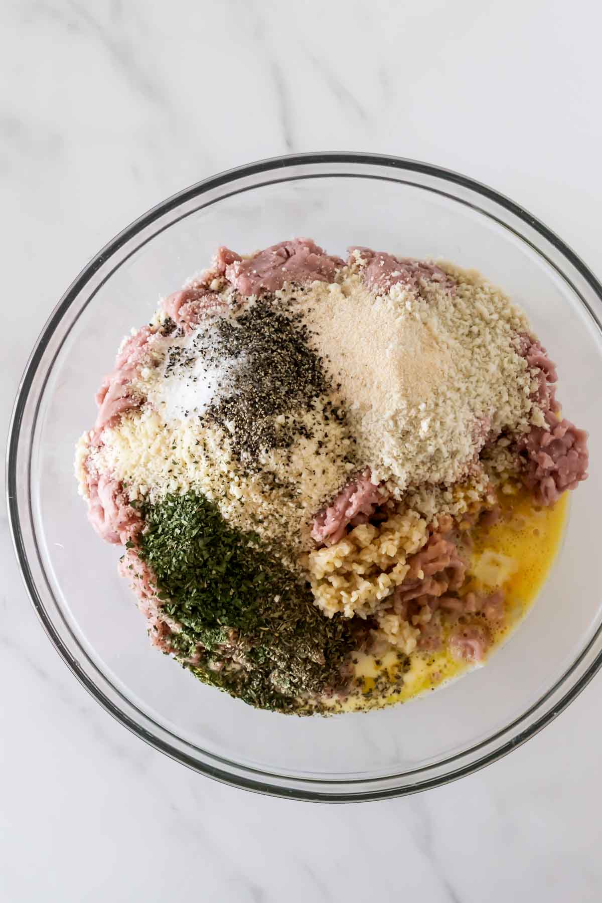 ground turkey mixture in a bowl on a white table for crockpot meatballs.