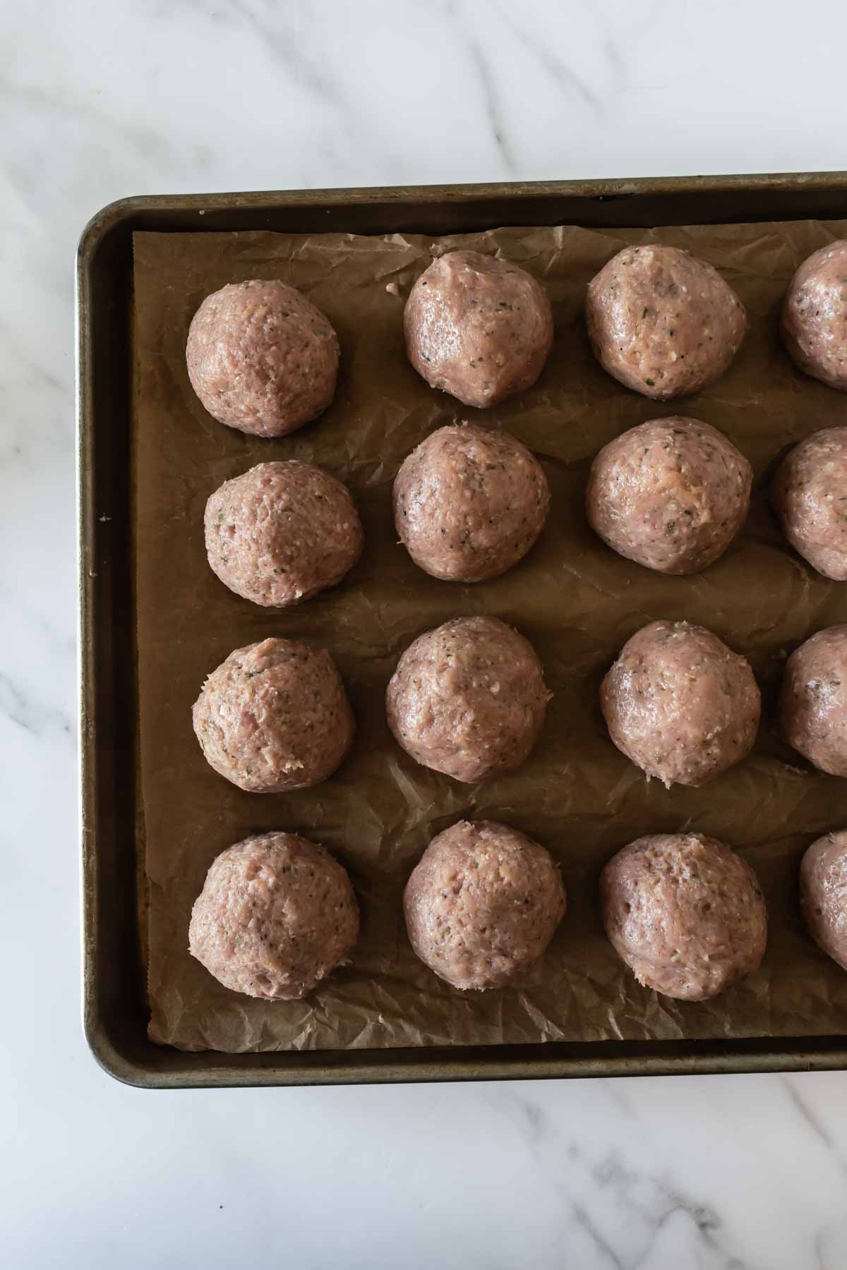 raw turkey meatballs on a baking sheet lined with parchment paper.