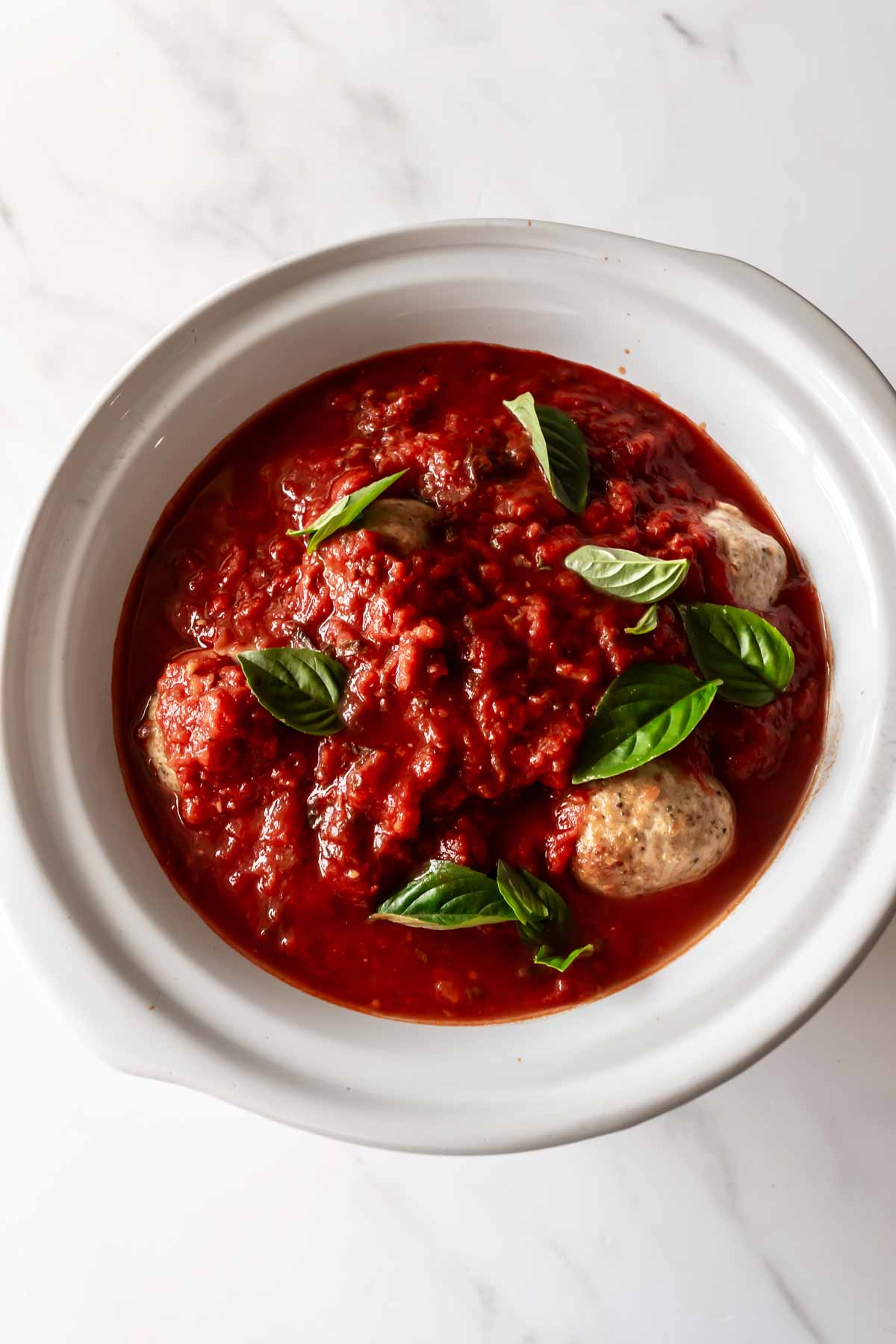 crockpot turkey meatballs covered in marinara sauce with basil leaves.