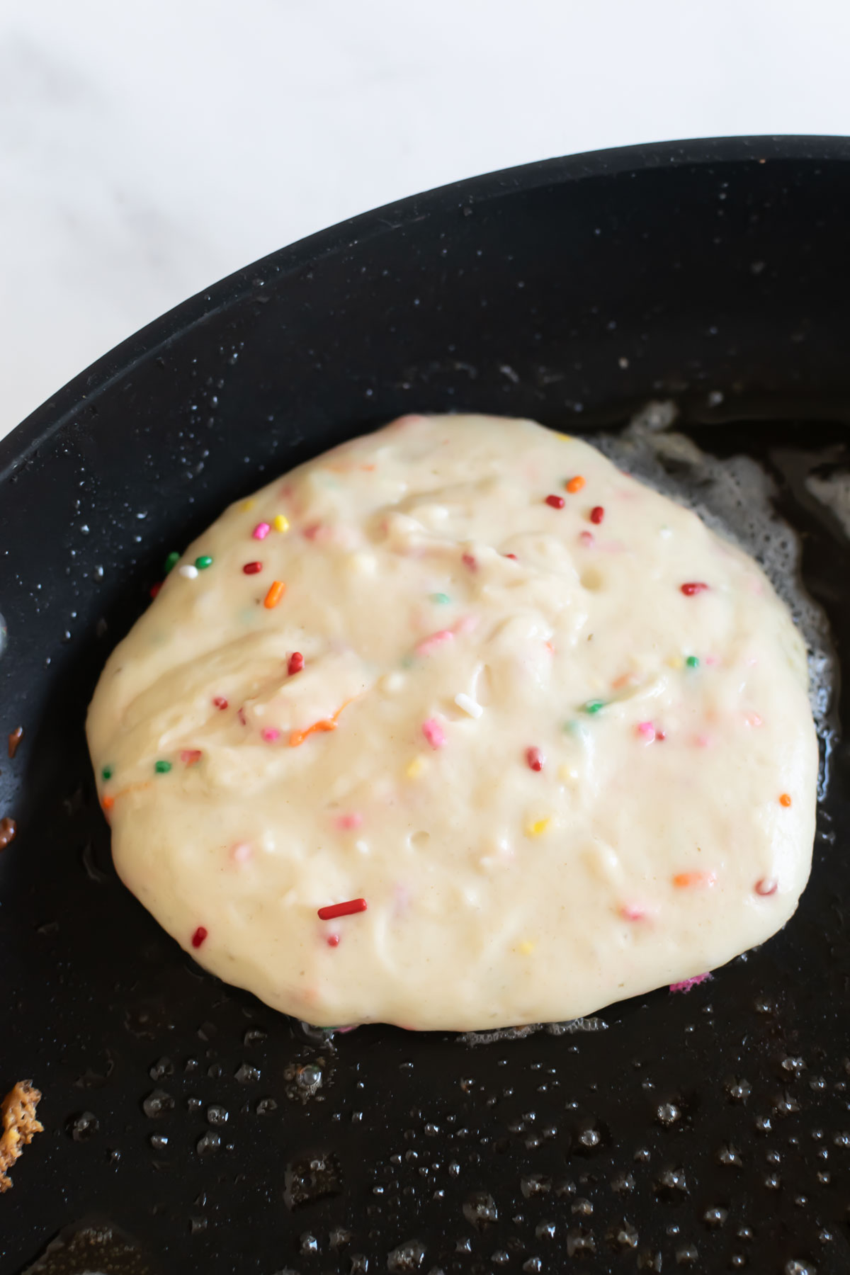 pancake batter in a black skillet.