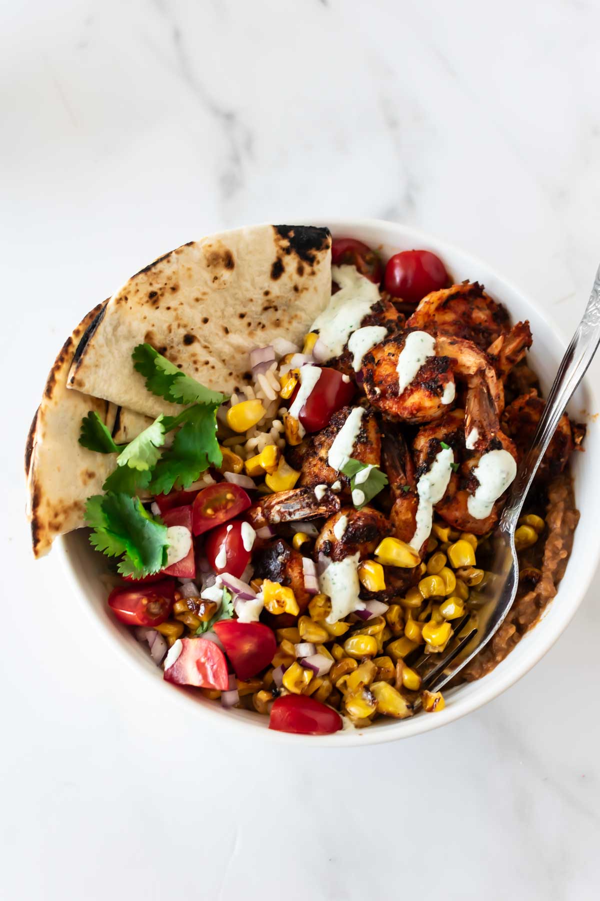 blackened shrimp bowl with rice, cajun shrimp, corn, tomatoes, cilantro, tortillas and sour cream.