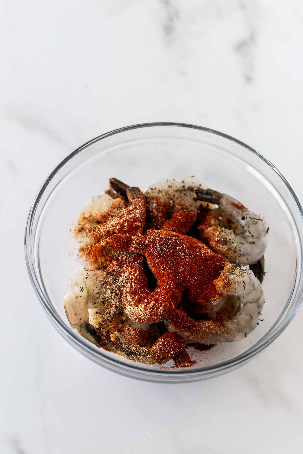 raw shrimp in a bowl topped with a spice rub.