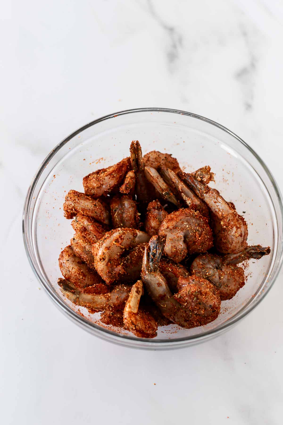 raw shrimp in a bowl coated in a dry spice rub.