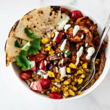 blackened shrimp bowl with rice, cajun shrimp, corn, tomatoes, cilantro, and tortillas.