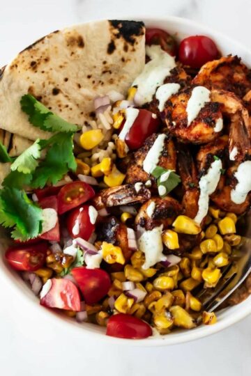 blackened shrimp bowl with rice, cajun shrimp, corn, tomatoes, cilantro, and tortillas.