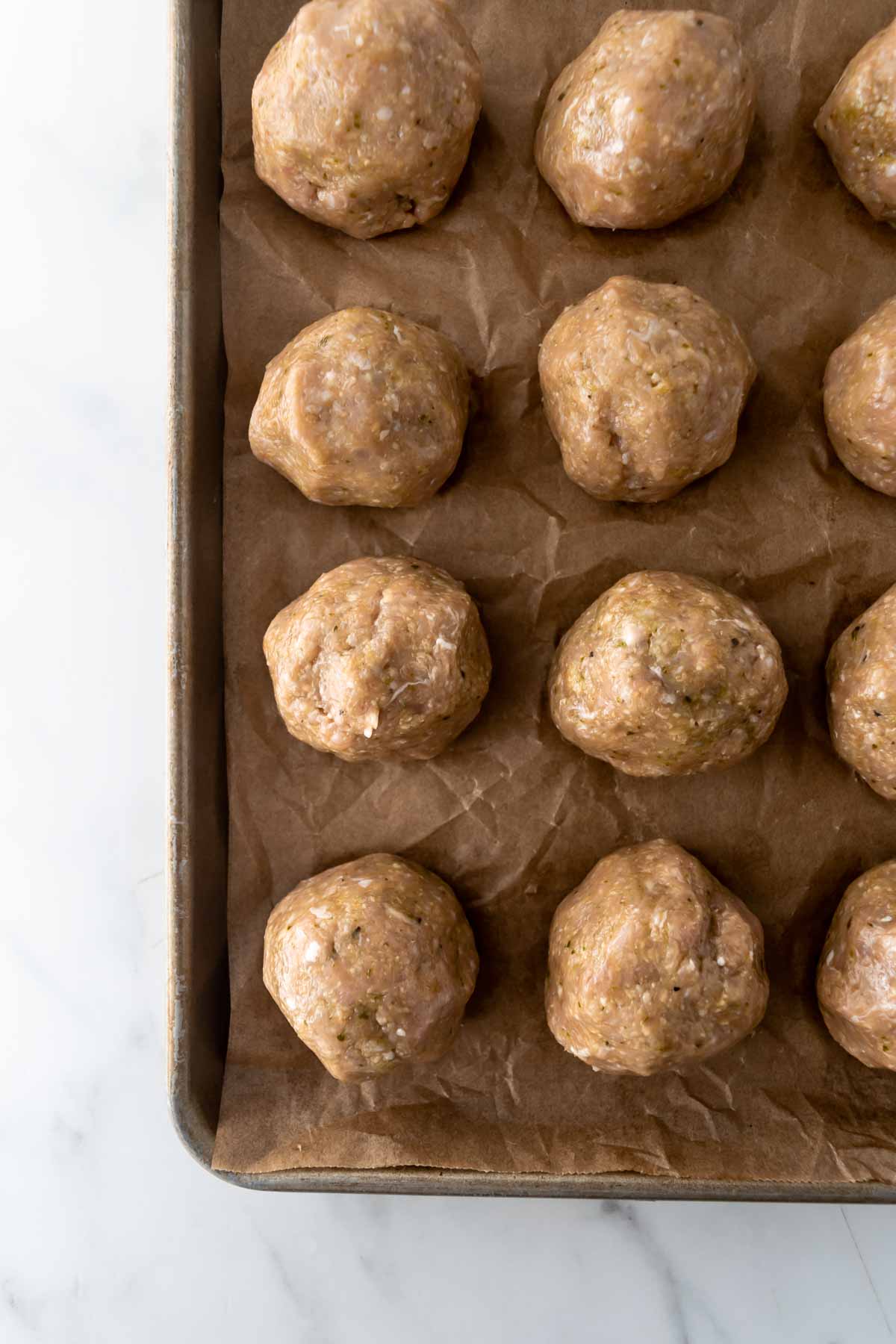 chicken meatballs with pesto on a baking sheet.