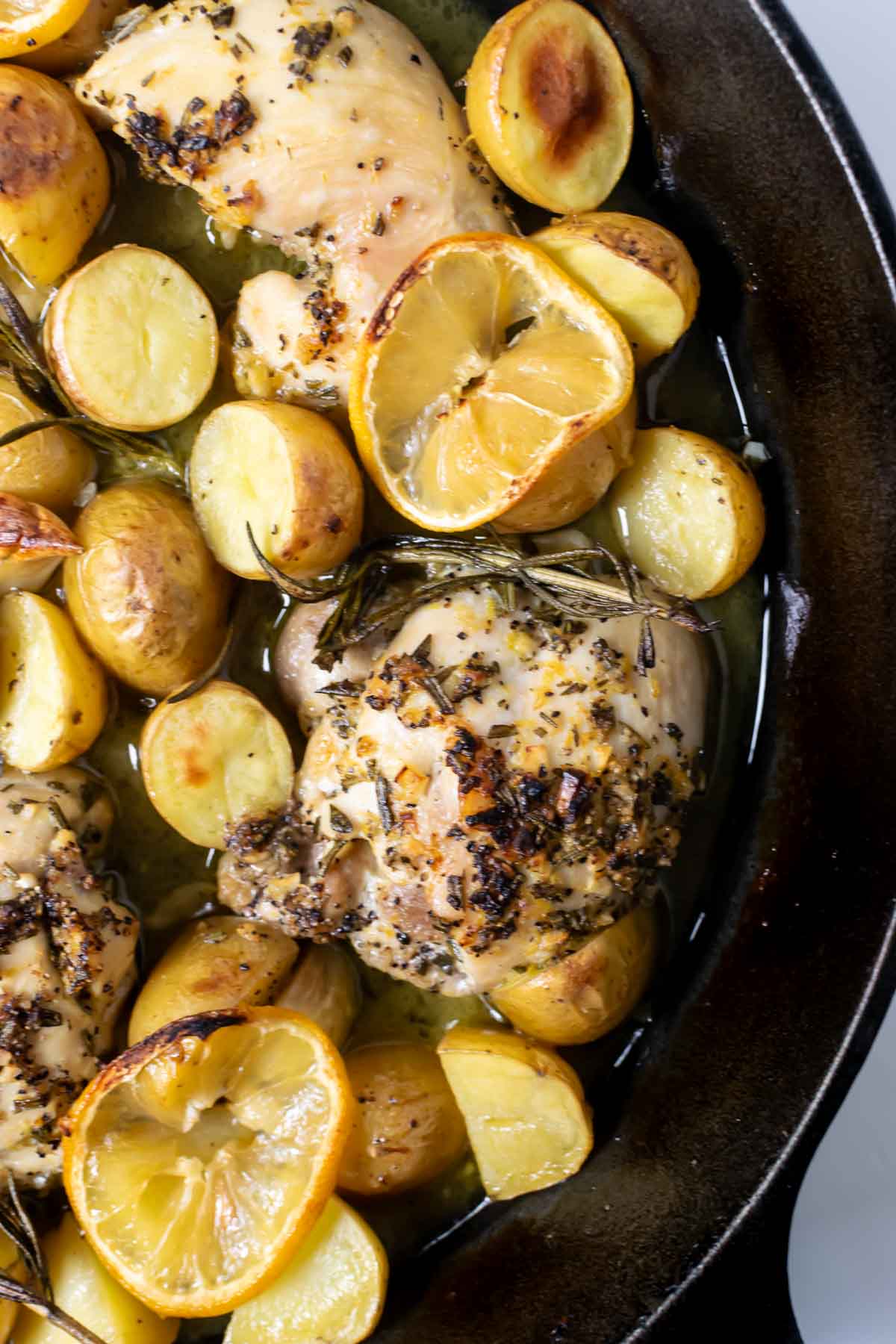 baked lemon rosemary chicken with lemon slices and potatoes.