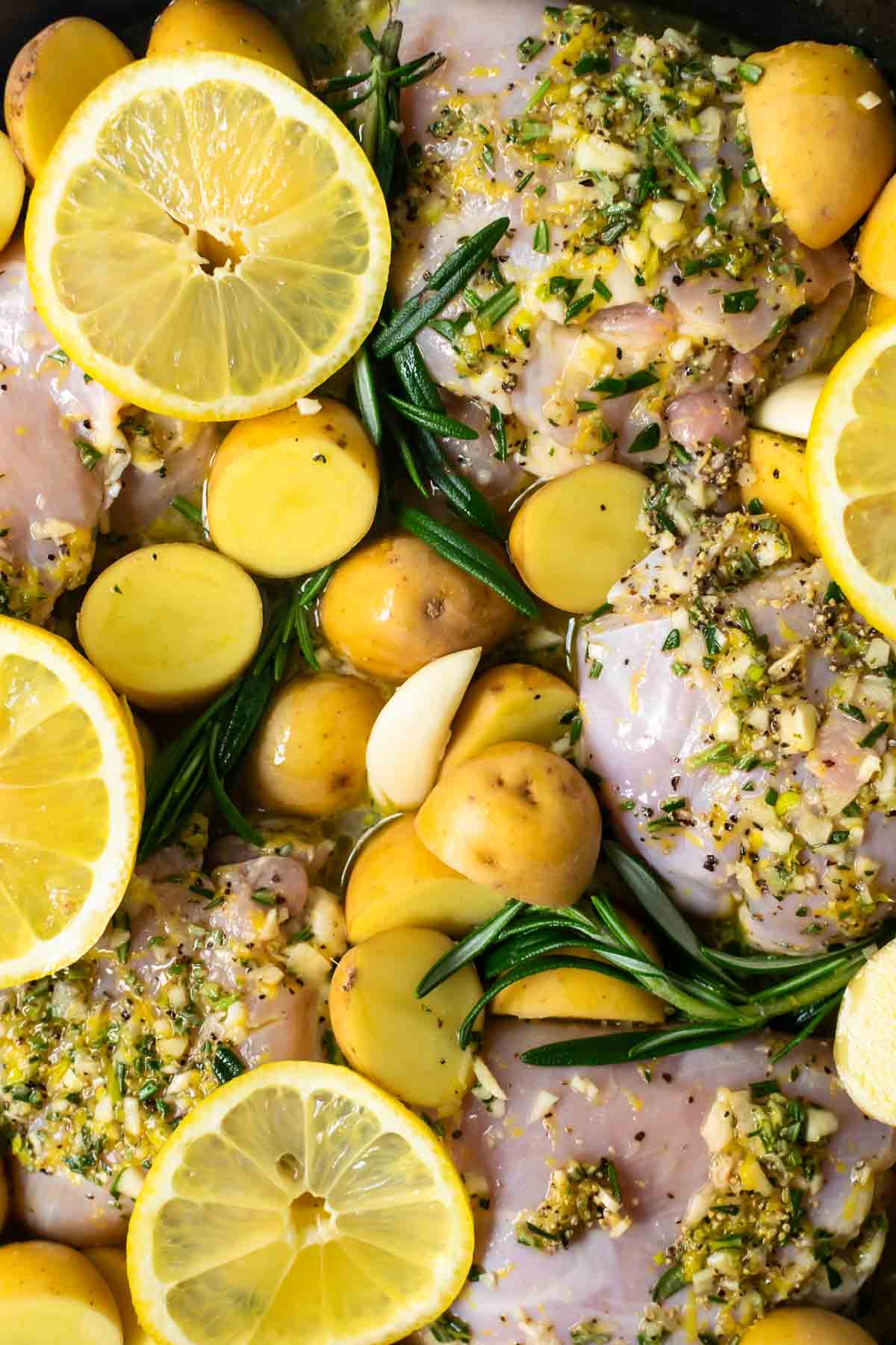 unbaked lemon chicken thighs with potatoes and rosemary.