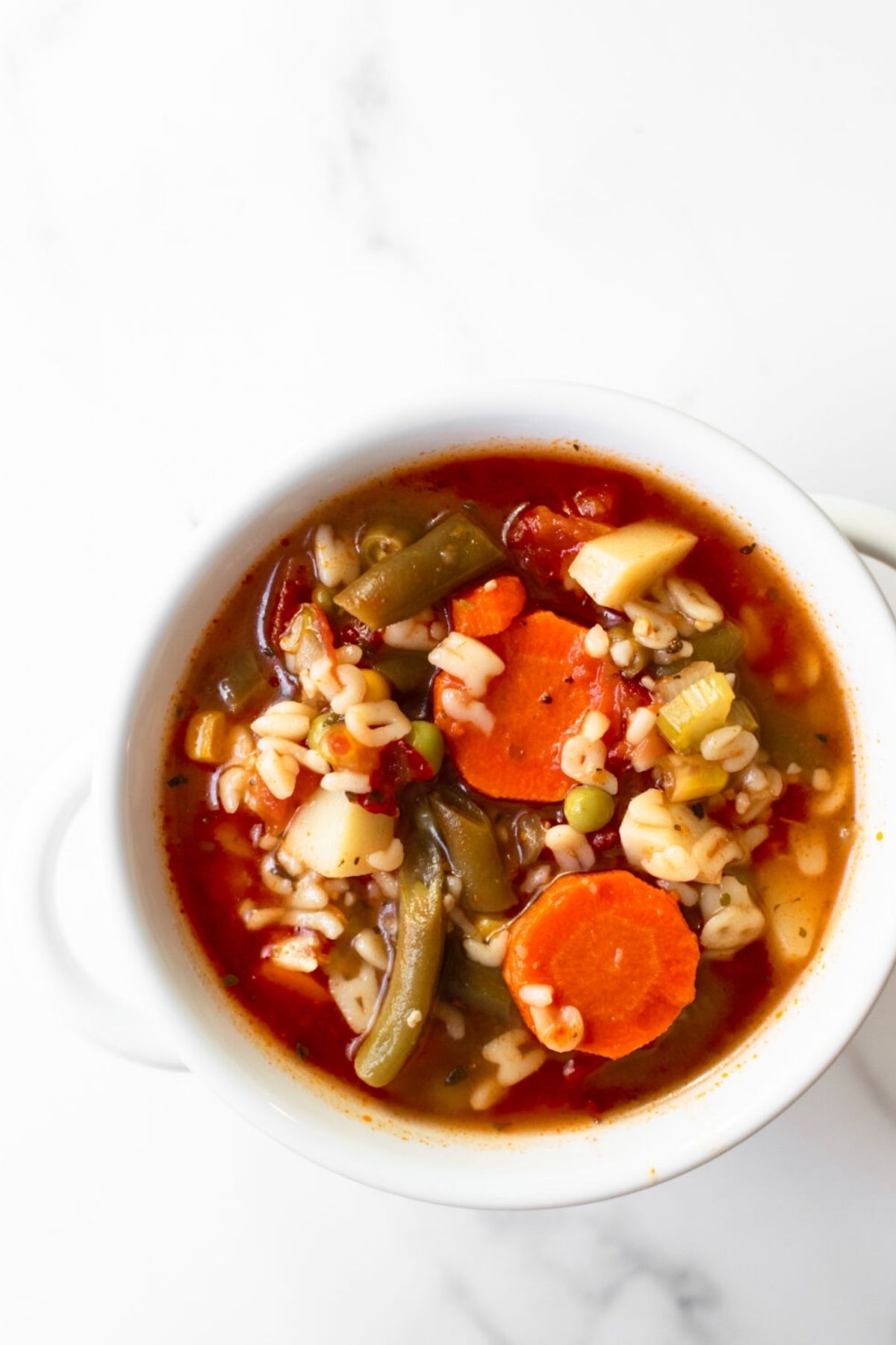 vegetable soup in a white bowl on a white table.