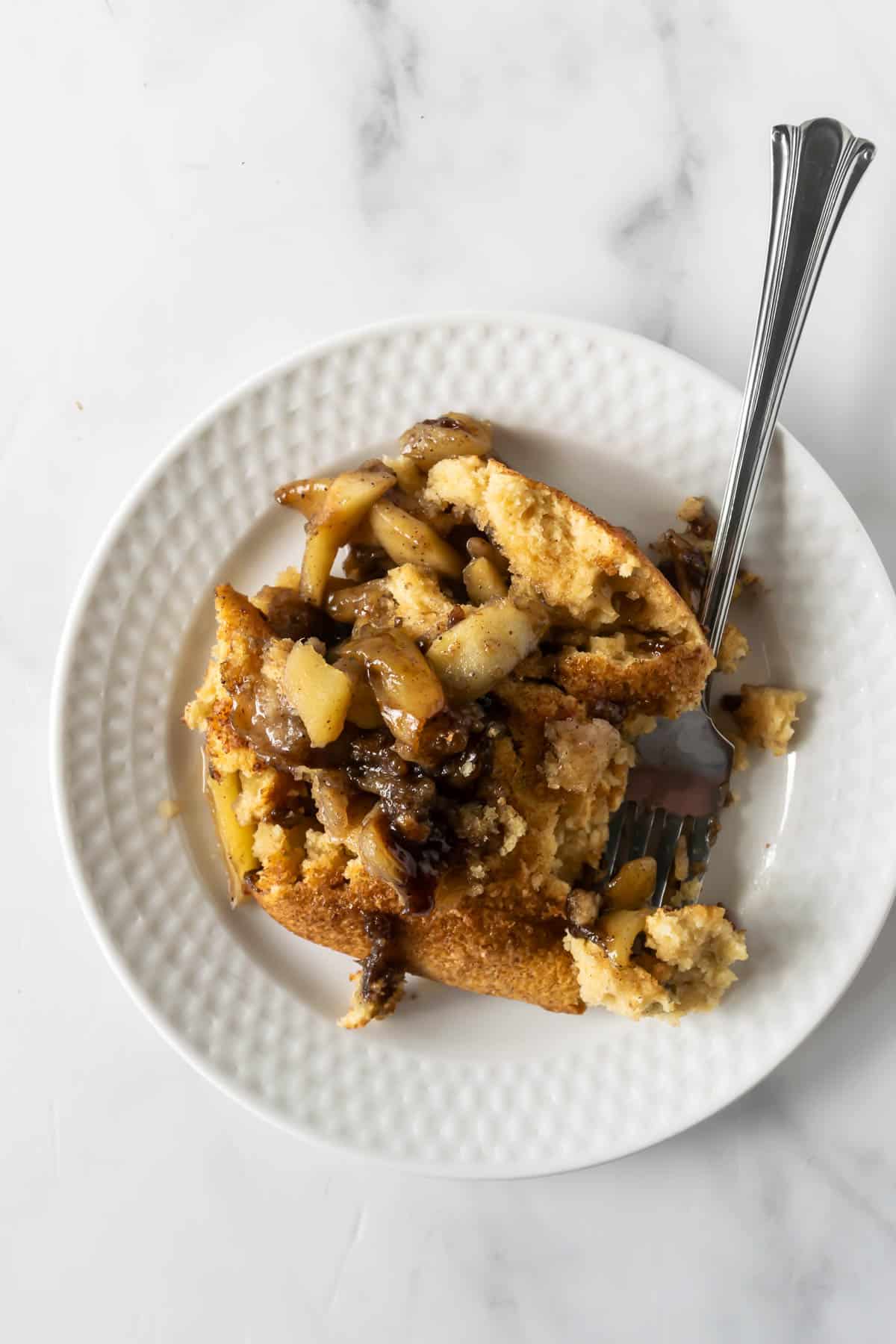 baked apple cinnamon pancake on a white plate with a fork.