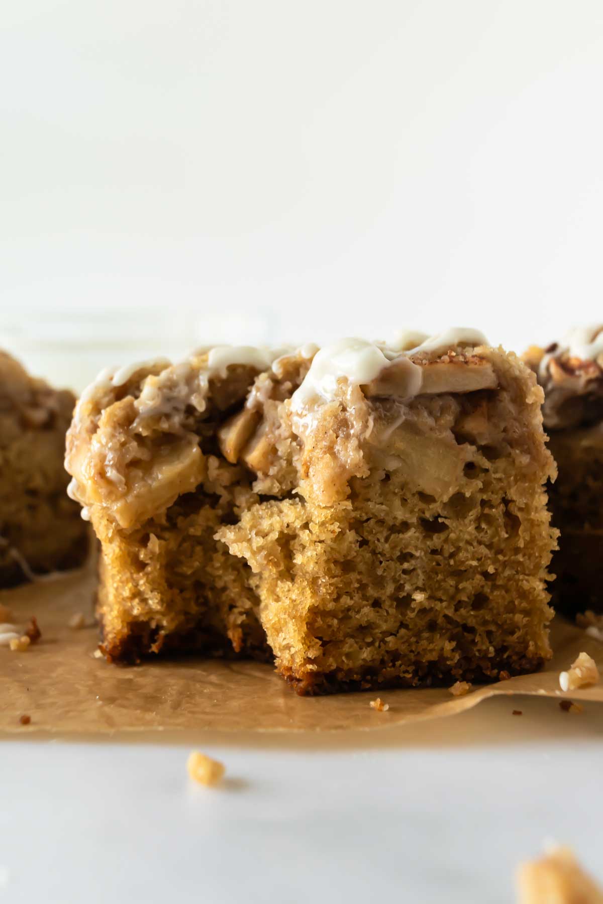 a bite taken out of apple crumb cake sitting on parchment paper.