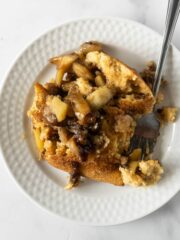 baked apple cinnamon pancakes with cooked apples on a white plate with a fork.