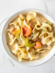 homemade creamy chicken noodle soup in a white bowl.