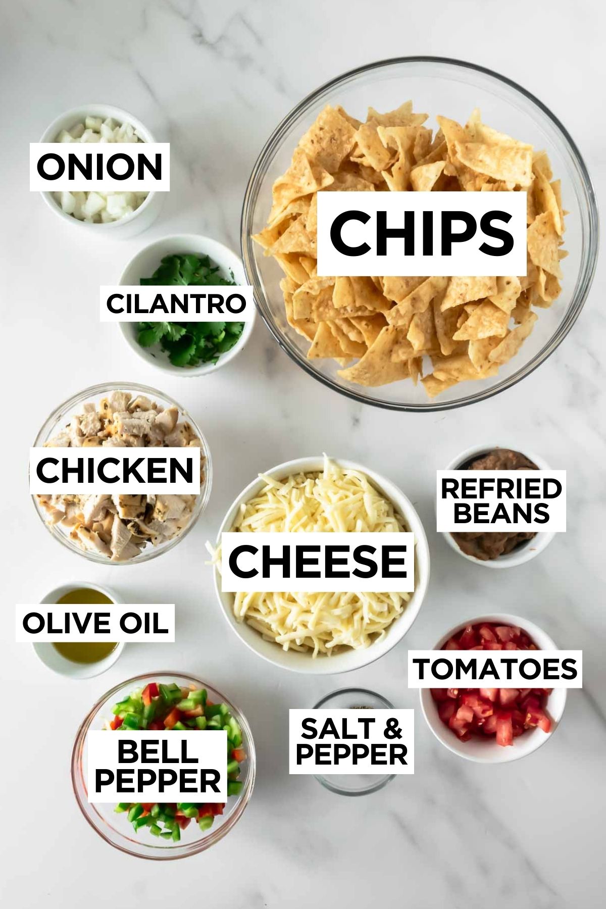 sheet pan nacho ingredients in bowls on a white table.