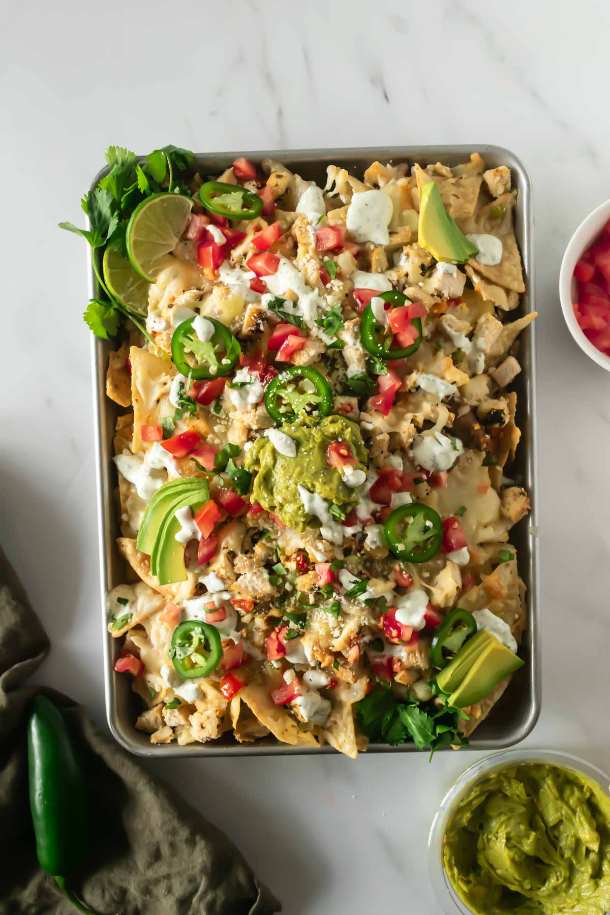 sheet pan nachos on a baking sheet with toppings.