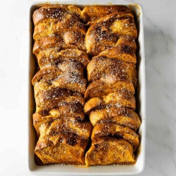 pumpkin French toast casserole in a baking dish topped with powdered sugar.