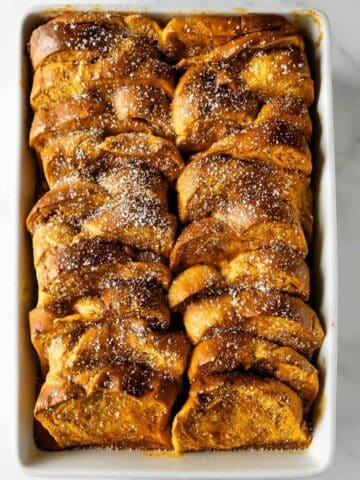 pumpkin French toast casserole in a baking dish topped with powdered sugar.