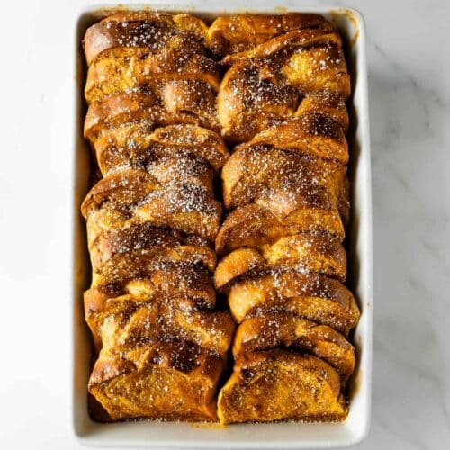 pumpkin French toast casserole in a baking dish topped with powdered sugar.