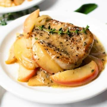 pork chops with apples on a white plate.