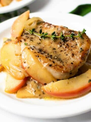 pork chops with apples on a white plate.