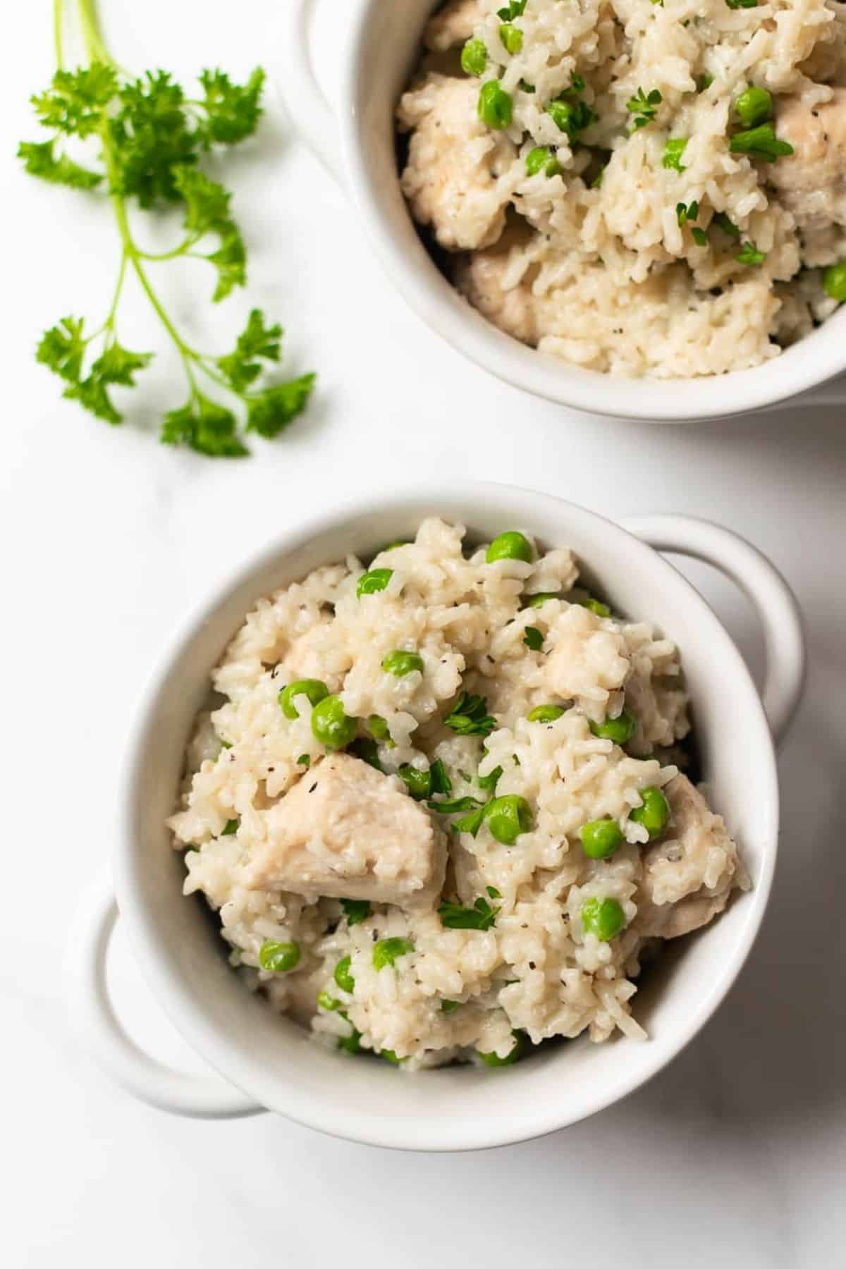 chicken and rice casserole with peas in a white bowl.