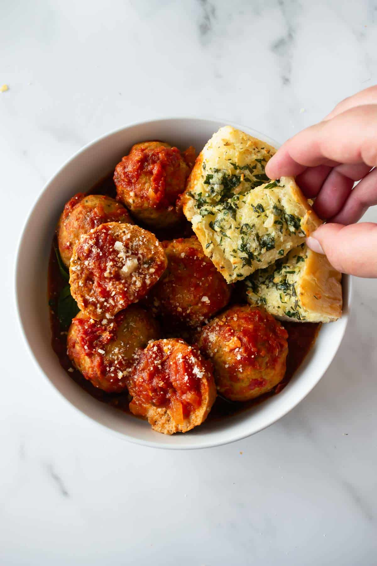 meatballs and garlic bread in a white bowl.