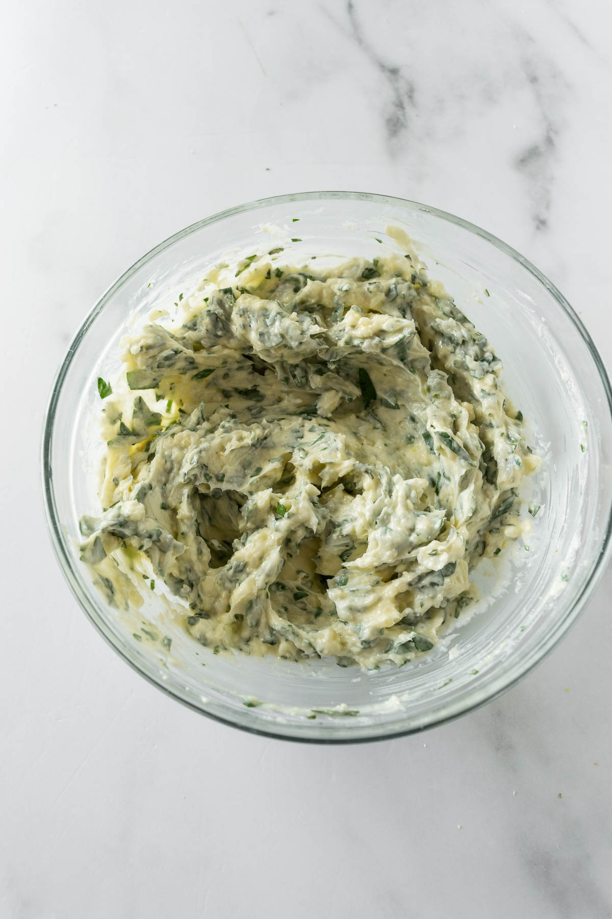 herb butter ingredients mixed together in a glass bowl.