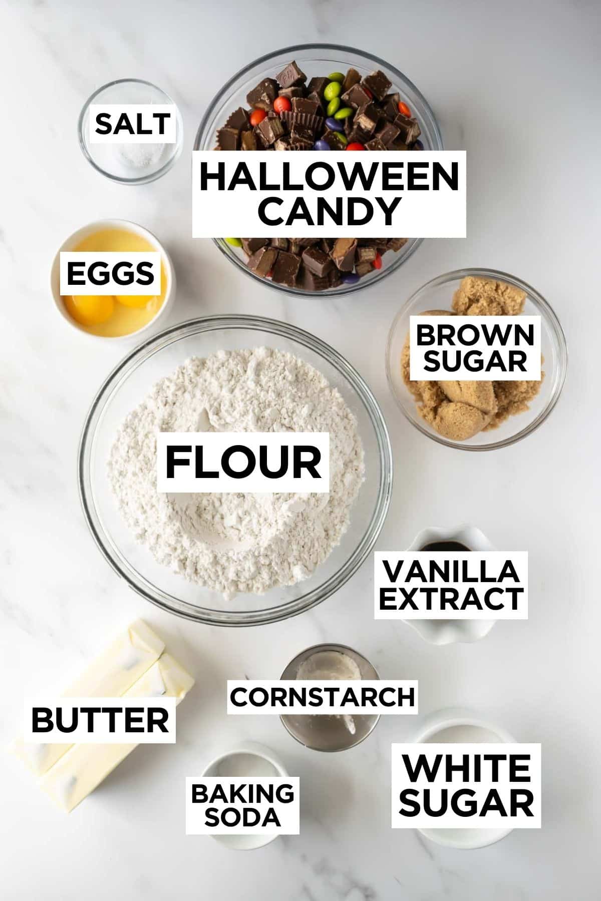 ingredients for halloween candy cookies in bowls on a white table with overlay text of ingredient names.