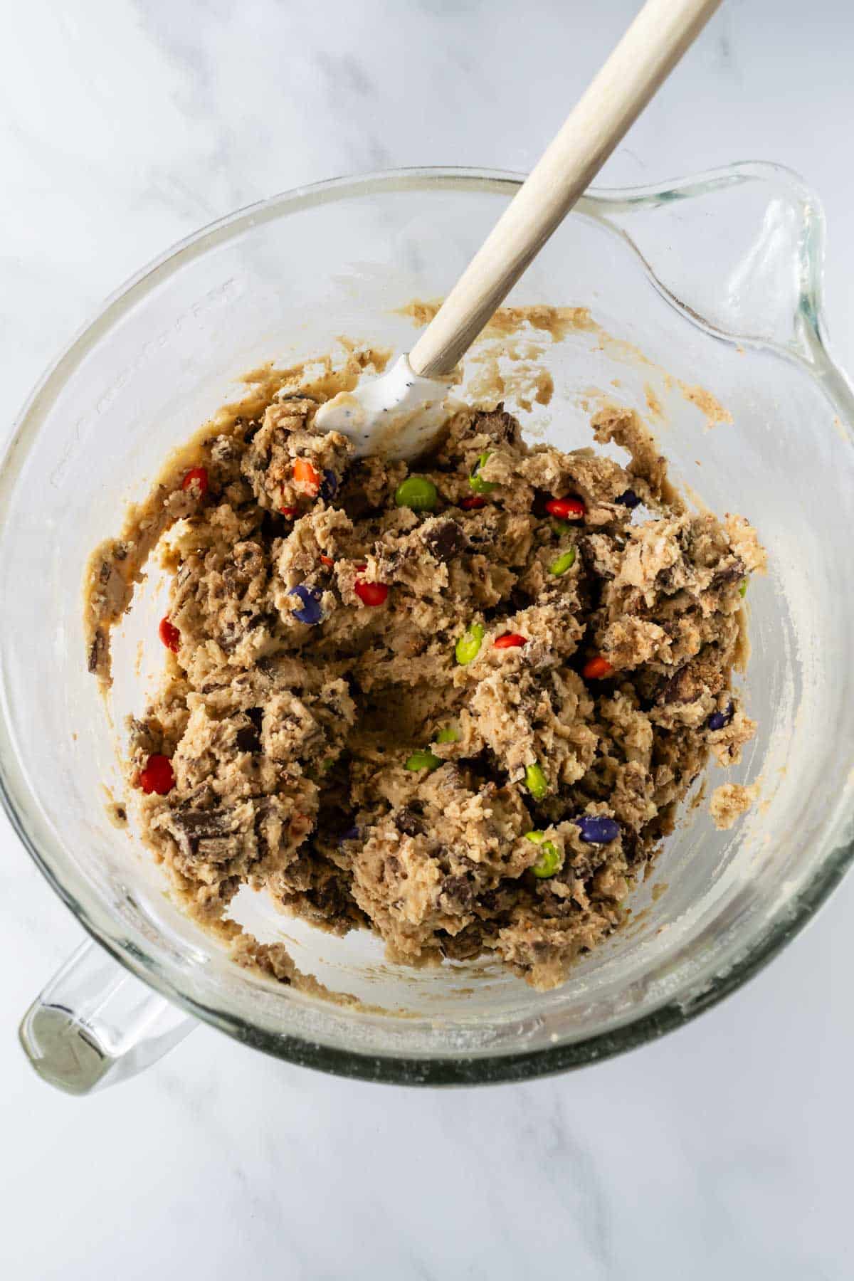 cookie dough with chopped Halloween candy in a mixing bowl.