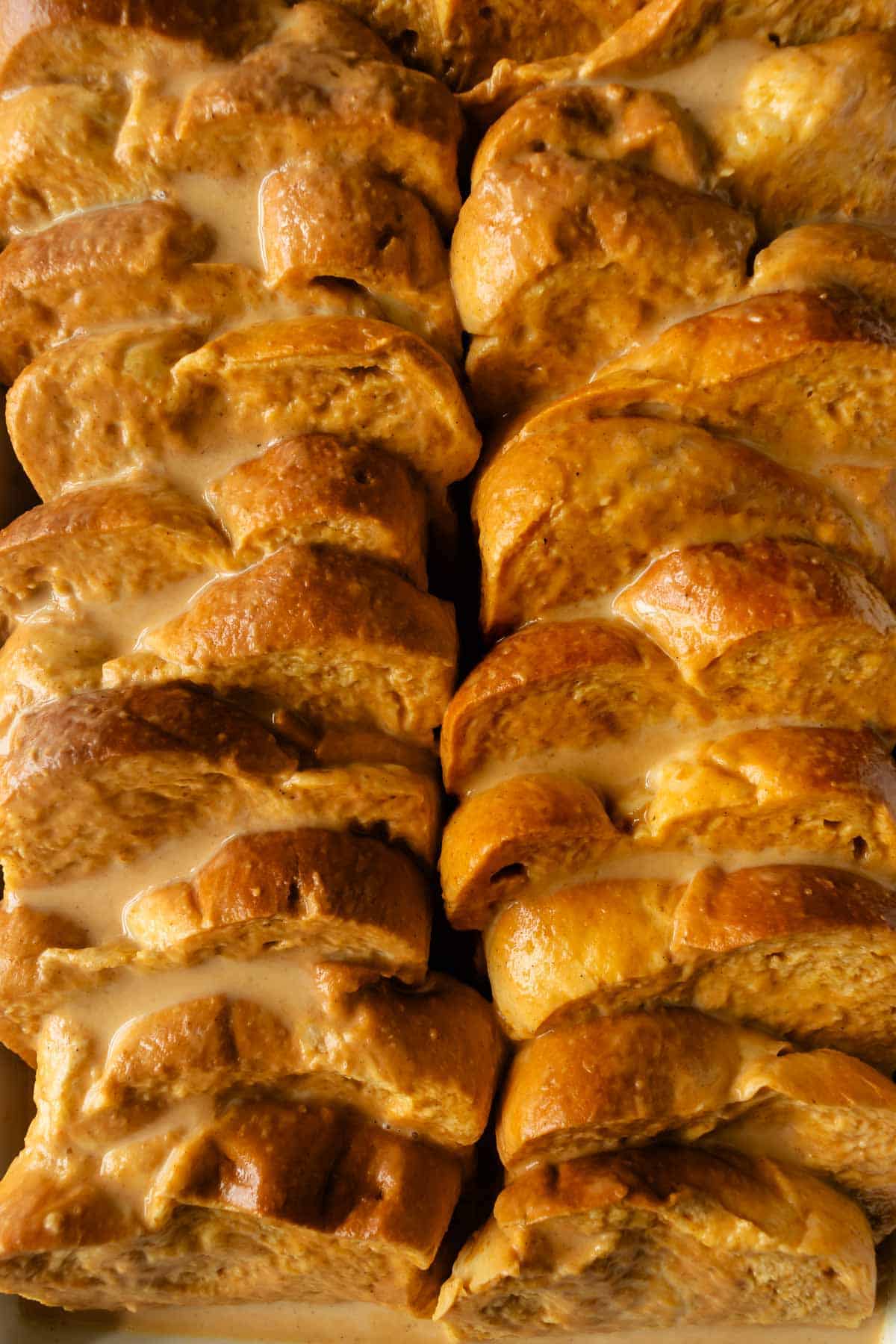 slices of brioche bread coated in a pumpkin egg custard stacked side by side.